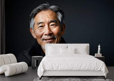 Warm-hearted studio portrait of smiling senior Asian man with grey hair and beard in black jacket against dark background Wall mural