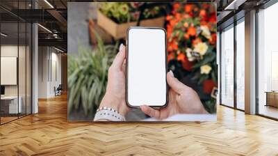 Blank smartphone screen , smartphone in a woman's hand in the background of a flower store, mock up delivery app  Wall mural