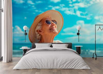 Cheerful elderly woman enjoying summer vacations on the sea beach, against the backdrop of blue sky Wall mural