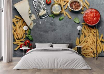 Pasta spaghetti or penne,  parmesan cheese, olive oil, spices, basil, tomato sauce and fresh tomatoes. top view. Italian food background. Wall mural