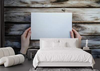 Blank Canvas - Minimalist Portrait of Person Holding White Paper on Softly Lit Wooden Surface in Cool Tones Wall mural