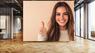 Positive Energy - Cheerful young woman showing thumbs-up gesture against a cozy beige backdrop with copyspace. Wall mural