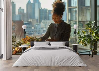 A young African American woman setting a table with eco-friendly Thanksgiving decorations in a modern apartment with large windows and city views Wall mural