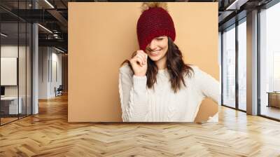 Beautiful natural looking young smiling brunette woman, wearing knitted scarf, covered with snow flakes. Snowing winter beauty concept. Wall mural