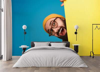 Cheerful man peeking out from behind poster Wall mural