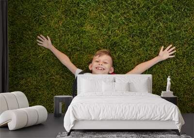 Cheerful pupil lying on grass in park Wall mural