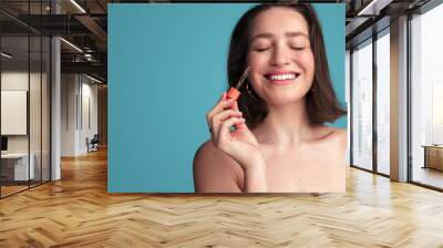 Cheerful woman applying serum on face Wall mural