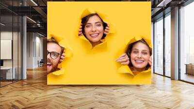 Cheerful young people looking out of ripped paper Wall mural