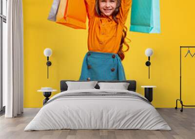 Excited little girl with shopping bags in raised hands Wall mural