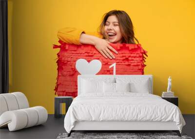 Excited young female hugging like sign Wall mural