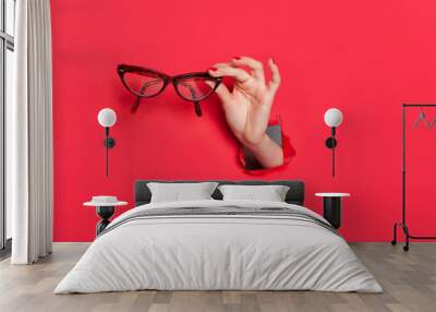 female hand in paper hole with glasses Wall mural