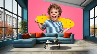 Happy curly boy laughing and holding skateboard Wall mural