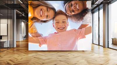 Happy diverse kids hugging against sky Wall mural