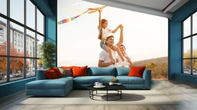 Happy family playing with kite in nature Wall mural