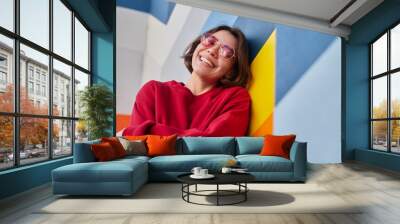 Happy female hipster leaning on colorful wall Wall mural