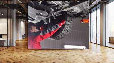 Male mechanic fixing car wheel Wall mural