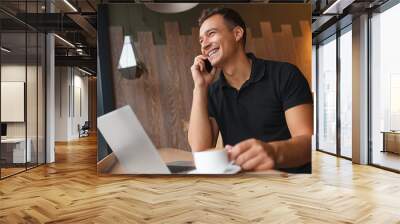 man sitting in cafe with phone, laptop and coffee Wall mural