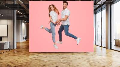 Merry young couple jumping together Wall mural