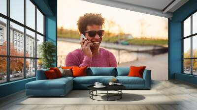 Portrait of a smiling guy using mobile phone. Wall mural