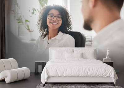 Smiling ethnic female talking with male coworkers in office Wall mural