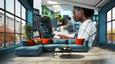 Young black woman working on laptop in office setting, African American female creating computer program code Wall mural