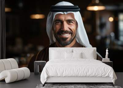 Arabic man indoor smiling while wearing traditional white Shemagh gown with black agal Wall mural