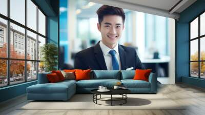 Asian male with a happy smile on his face, wearing a formal black suit, working in an office background Wall mural