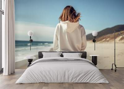 Back of hip blond tan woman wearing white thick oversized hoodie on the beach landscape view Wall mural