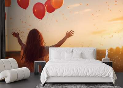 Back silhouette view of an happy young woman releasing balloons in the sky at sunset in summer background with copy space Wall mural