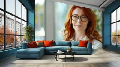 Beautiful 45 years old gentle ginger red hair caucasian woman, wearing glasses, formal slick hairstyle, smooth face in a modern office building, wearing white shirt, beside a huge window Wall mural