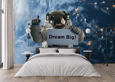 Dream big concept image with an astronaut in space holding a board sign with written words Dream Big Wall mural