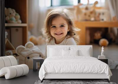 Full-body shot of a happy 3-year-old girl playing on the carpet in the living room with toys around. She is wearing a light beige home outfit Wall mural