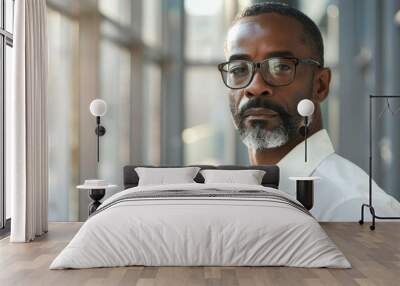 Handsome 45 years old gentle black African American man, wearing glasses, formal slick hairstyle, smooth face in a modern office building, wearing white shirt, beside a huge window Wall mural