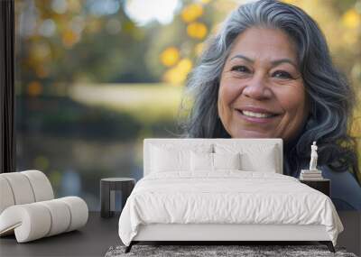 Latino woman in her 50s who exudes happiness and a sense of feeling truly alive in a beautiful natural park near a lake, genuine smile on her face, relaxed and confident, latin female who found joy Wall mural