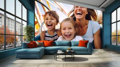 Mother and two children family riding a rollercoaster at an amusement park experiencing excitement, joy, laughter, and fun Wall mural