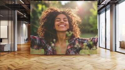 Portrait of a free happy latin american woman with open arms enjoying life in meadows and nature background , young joyful latina female with good mental health Wall mural