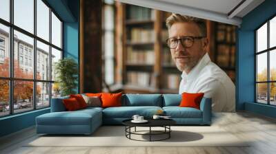 Portrait of an handsome blond hair caucasian white man in his 40s wearing glasses with formal slick hairstyle and smooth face wearing a white shirt in a luxury ancient library Wall mural