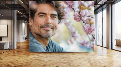 Portrait of an handsome South American hispanic man posing in front of a blooming cherry tree , close-up view of a cheerful beautiful latino white middle aged male in an outdoor park Wall mural