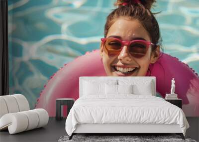 Portrait of happy young caucasian woman in a pink rubber swimming pool ring on at hotel club swimming pool during summer vacation Wall mural