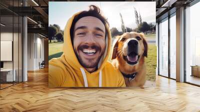 Selfie picture of a young happy man walking his dog in a park , smiling guy and pet having fun together outdoor , friendship and love between humans and animals Wall mural