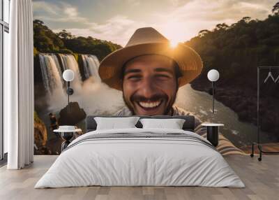 Selfie picture of an handsome tourist visiting national park in front of beautiful waterfall , happy man traveler with a hat enjoying freedom in the nature and sunset Wall mural