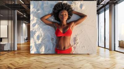 Top down view of a black African American beautiful young woman sunbathing in swimwear on a white sand beach on sunny summer day Wall mural