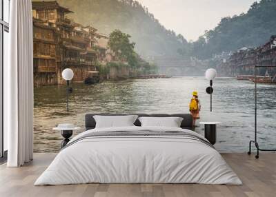 Woman on steeping stones bridge over Tuo Juang river seems walking on water in Fenghuang ancient town Hunan China Wall mural