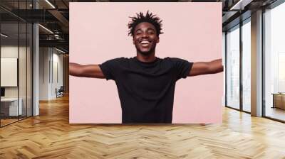 Young black African man with open arms isolated on pink background , studio shot of an handsome afro American guy with happy smiling face welcome with open arms on pale pink color backdrop Wall mural