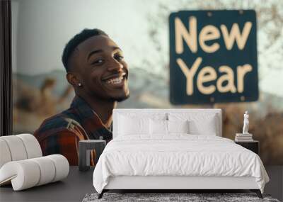 Young happy man positive about the coming New Year showing an happy face in front of a New Year sign representing hope and trust in the future for the Happy New Year Wall mural