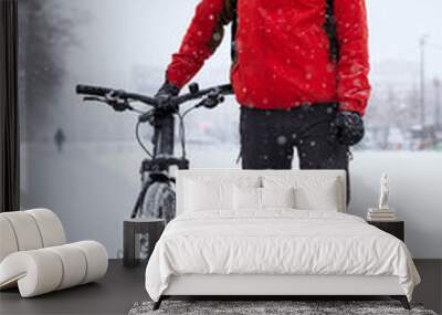 Caucasian cyclist stands next to a bicycle on a winter snowy day Wall mural