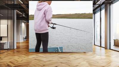 Pre-teen girl standing with fish rod, female fisherman catching the fishes from pier Wall mural