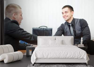 young business man shaking hands with colleague across the table Wall mural