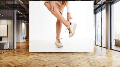 Beautiful sneakers on woman legs in the studio on white background. Fashionable shooting of a young girl with beautiful legs Wall mural