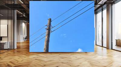 Old power line pole against blue sky in sunny day Wall mural